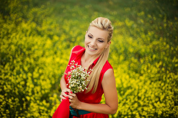 Naklejka na ściany i meble Beautiful young blonde woman in red dress with camomile flowers