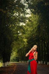 Portrait of dancing woman at forest in red dress