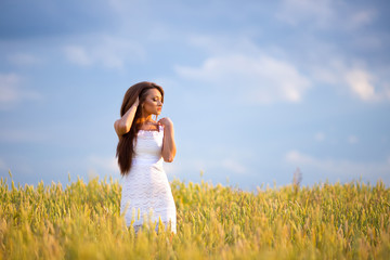 Naklejka na ściany i meble beautiful woman posing in yellow wheat field