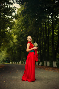 Portrait of dancing woman at forest in red dress