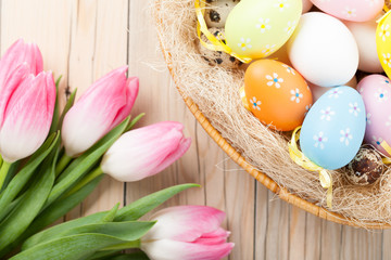 Colorful Easter eggs in the basket with pink tulips