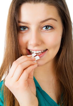 Young charming smiling woman puts in mouth chewing gum, close up