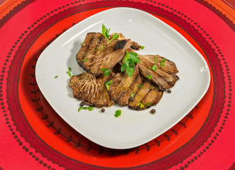 Antipasto di funghi pleurotus alla griglia su sfondo rosso