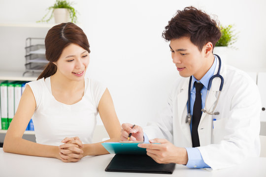 asian doctor talking with female patient in  office