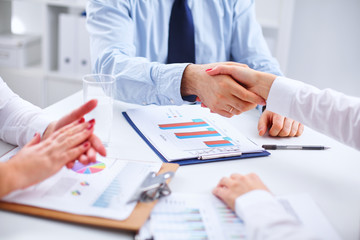 Business people handshake, sitting at the table