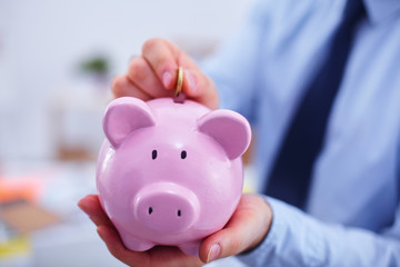 Businessman putting  money into a piggy bank isolated on white