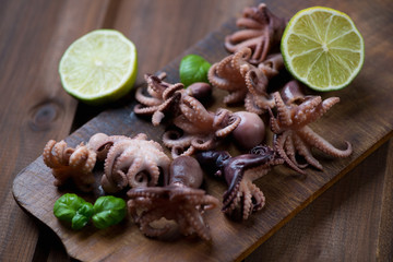 Octopuses with lime and basil over rustic wooden chopping board