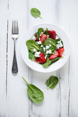 Spinach, strawberry and cheese salad, white wooden background
