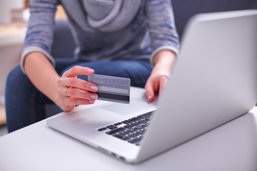 Fototapeta premium Woman sitting at the desk, shopping with laptop and credit card
