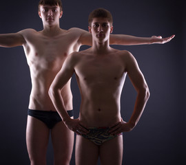 Fototapeta na wymiar Two muscular men posing on a dark background.