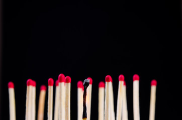 many red matches on black background (one match burned)