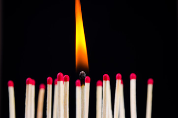 many red matches on black background (one match burns)