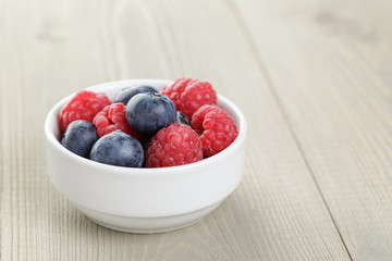 blueberries and raspberries in bowl on wooden table