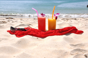 Pair of fruit shakes, red shawl and sunglasses on the beach of P