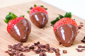 Chocolate dipped strawberries, chocolate pieces around him.