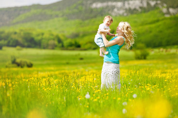 young woman playing with her child in flowers field