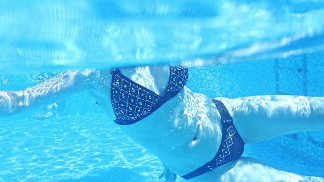 Young pretty woman swimming in the blue pool