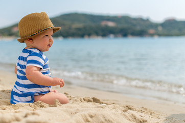 Little baby boy sitting on the sand