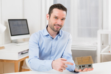 Young attractive real estate agent with a miniature house