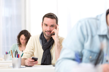 Young attractive student using his mobile during classes
