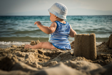 Cute baby boy playing with beach toys