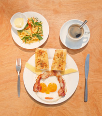 Fried eggs with bacon, toasts, green mango salad and coffee