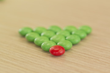concept : one of many. Plenty of green and one red candy