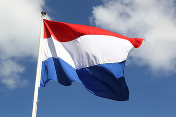 Dutch national flag on liberty day against blue sky with clouds