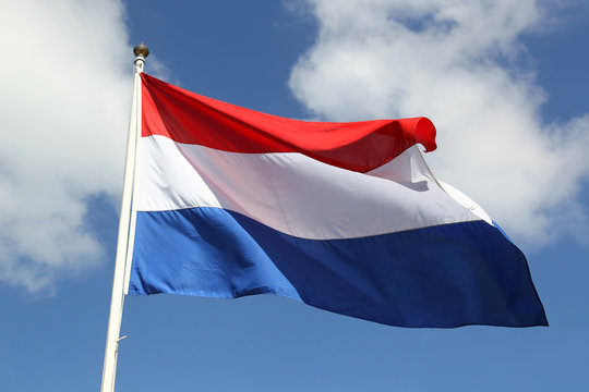 Dutch national flag on liberty day against blue sky with clouds