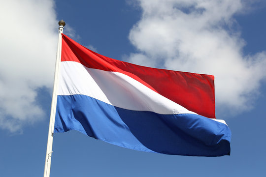 Dutch national flag on liberty day against blue sky with clouds