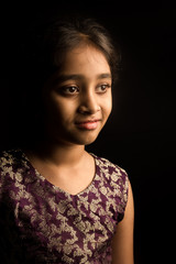 Closeup portrait of happy indian girl isolated on black backgrou