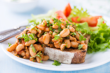 Stewed white beans in tomato sauce on toasted bread