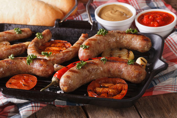 grilled sausages on a grill pan, buns with sauce. Horizontal