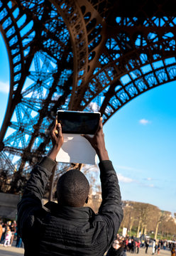 Modern tourist: man taking picture of Eiffel Tower with tablet