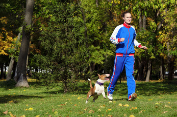 Naklejka na ściany i meble Young attractive sport girl jogging with dog in sunny park