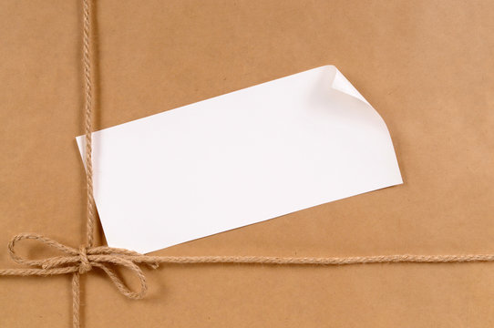 Brown paper package parcel background tied with string or rope and blank message or address label photo