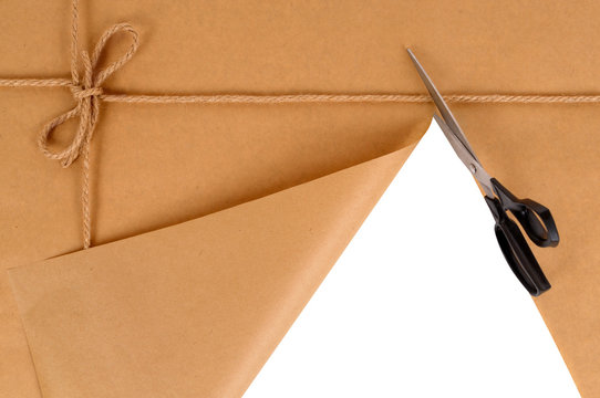 Brown paper package parcel background tied with string or rope being cut open with scissors photo