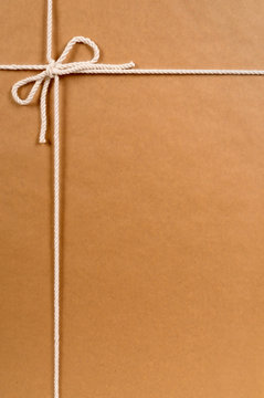 Brown paper package parcel background tied with string or rope photo vertical