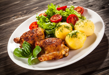 Barbecued chicken legs with boiled potatoes and vegetables