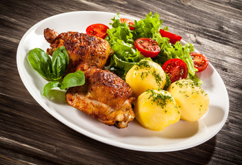 Barbecued chicken legs with boiled potatoes and vegetables