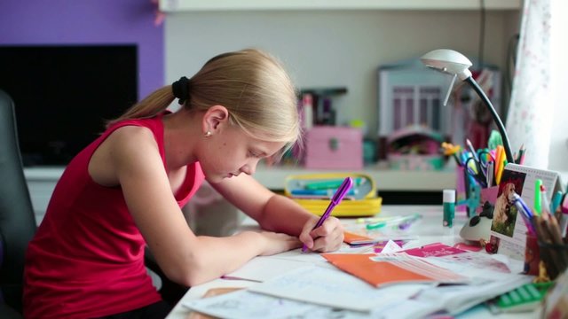 Pretty school girl at home, writing a homework, studying