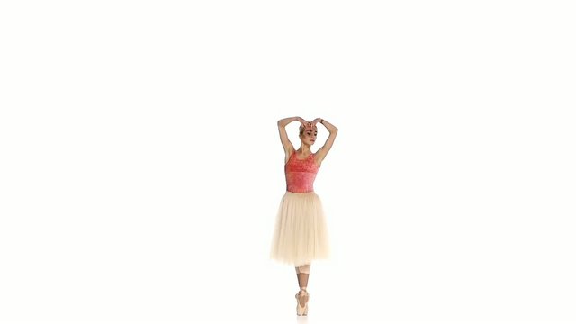 Young ballerina making dance trick, grands battements, on white