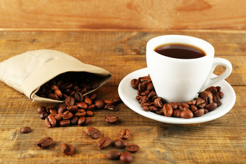 Cup of coffee with beans on rustic wooden background