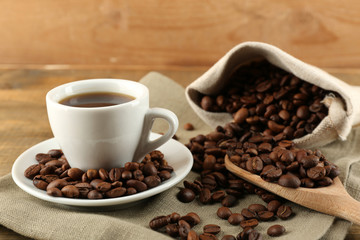 Cup of coffee with beans on rustic wooden background