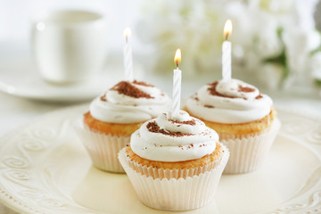 Delicious birthday cupcakes on table on light background