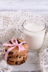 Tasty cookies and glass of milk on color wooden background