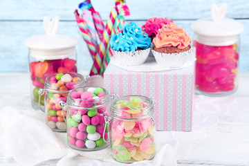 Multicolor candies in glass jars and cupcakes