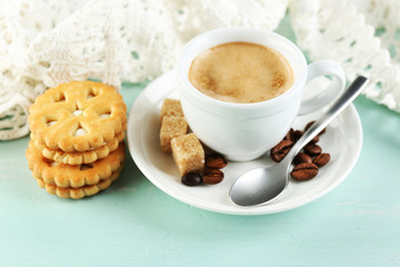 Cup of coffee and tasty cookie on color wooden background
