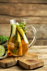 Glass ewer with fresh organic cucumber water on wooden table