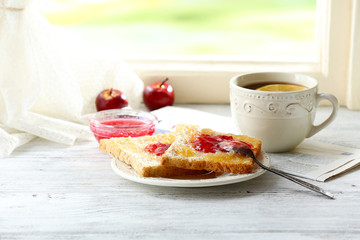 Toasts with jam on plate and cup of tea on bright background